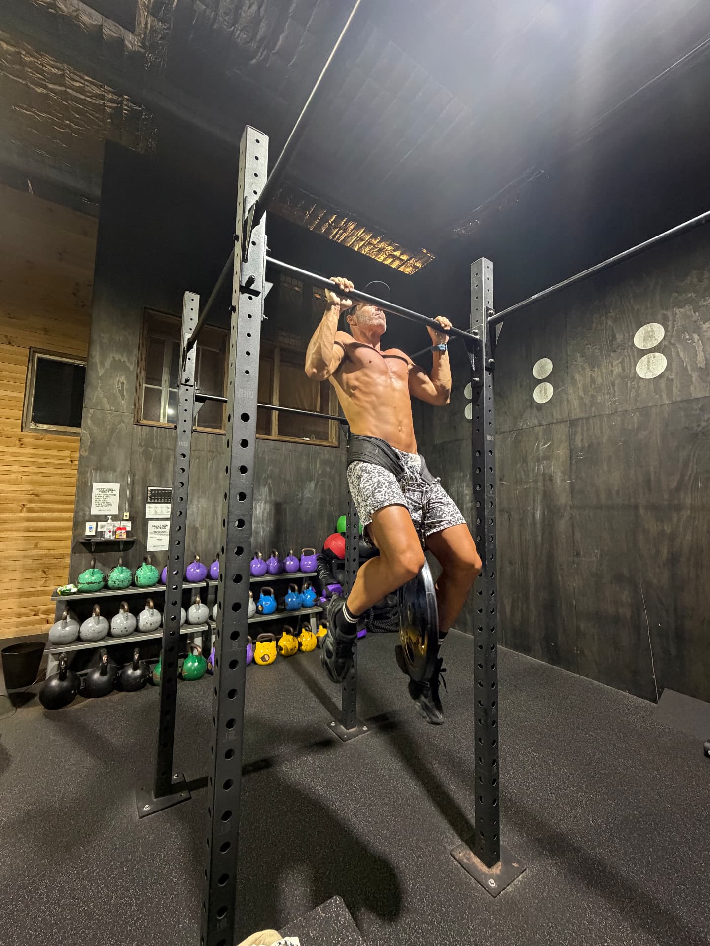 Jordan doing weighted pull ups in a garage gym
