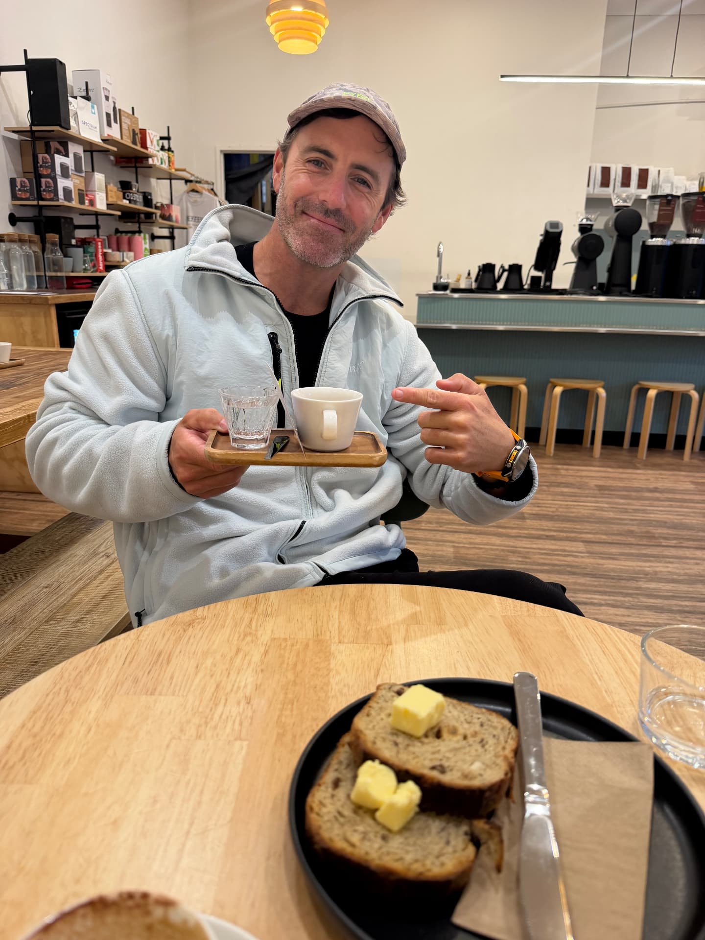 Jordan holding an espresso and toast at a specialty coffee shop